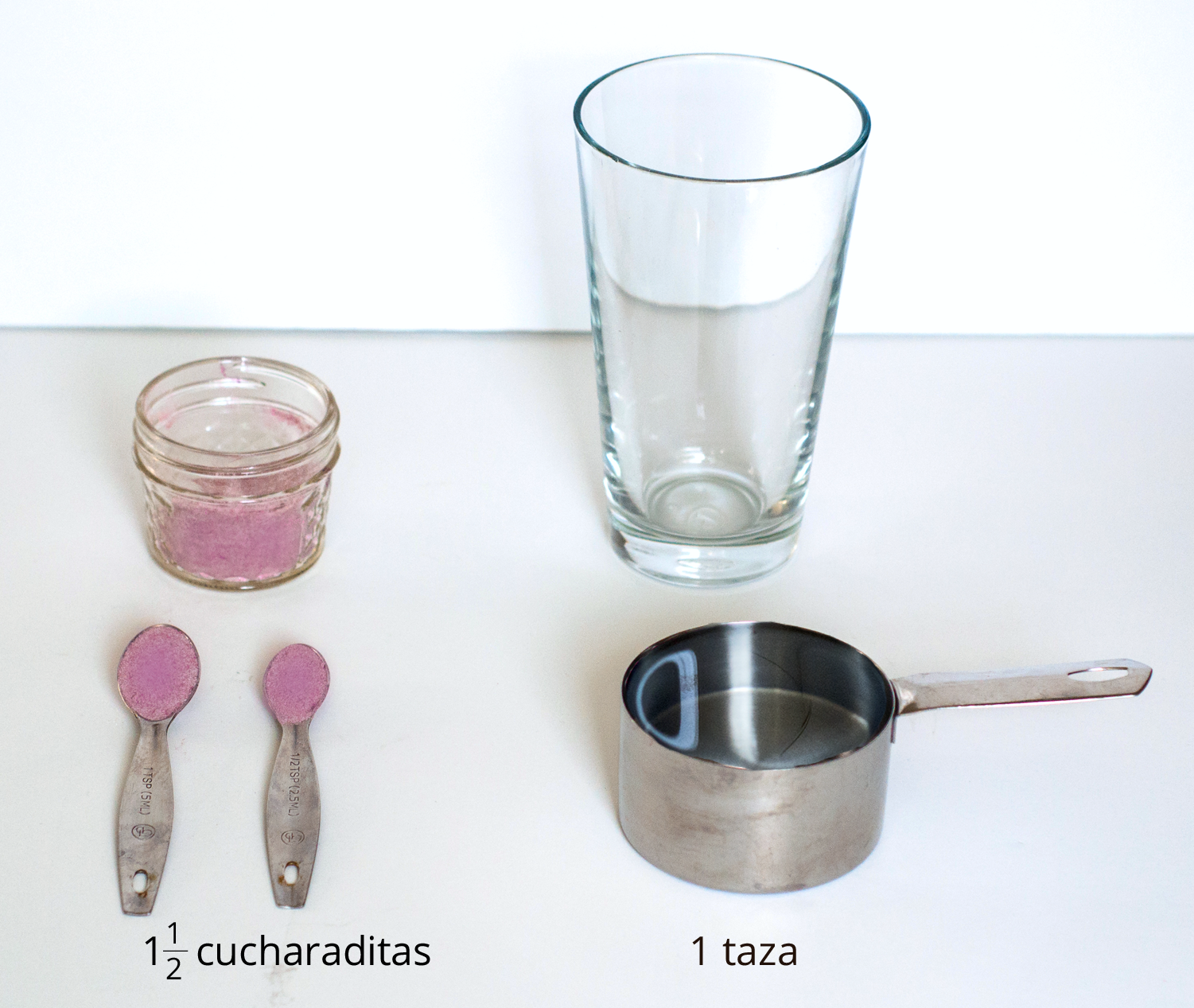 A picture of a glass, drink mixture in a container, one and a half teaspoons of drink mix, and 1 measuring cup.