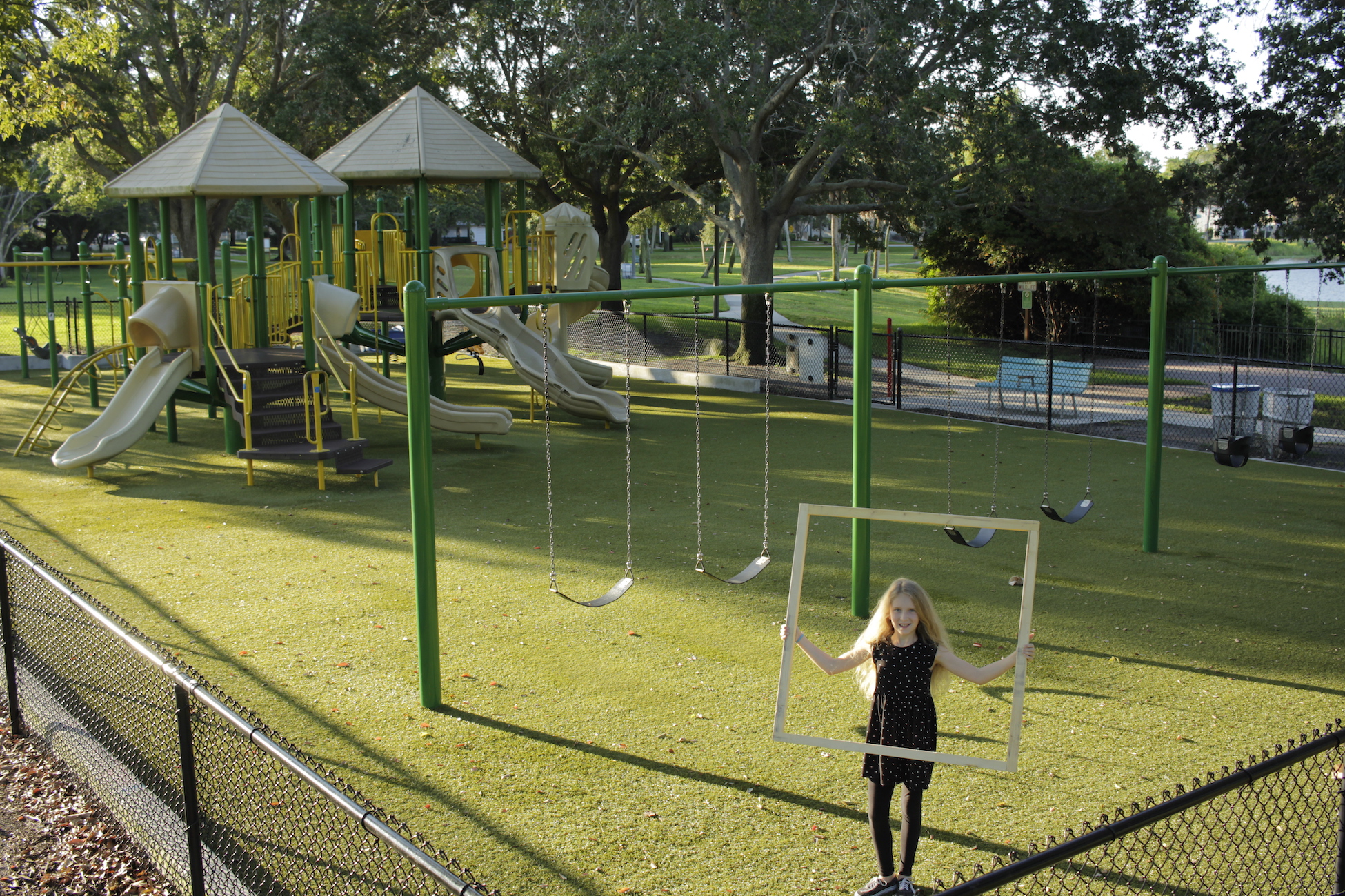 Photograph. P<span>erson holding large square. P</span><span>layground in background.</span>