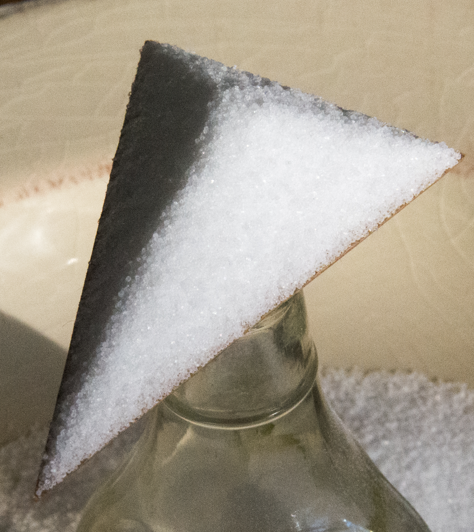 <p>Cardboard triangle on top of glass bottle, with salt on top of triangle.</p>
