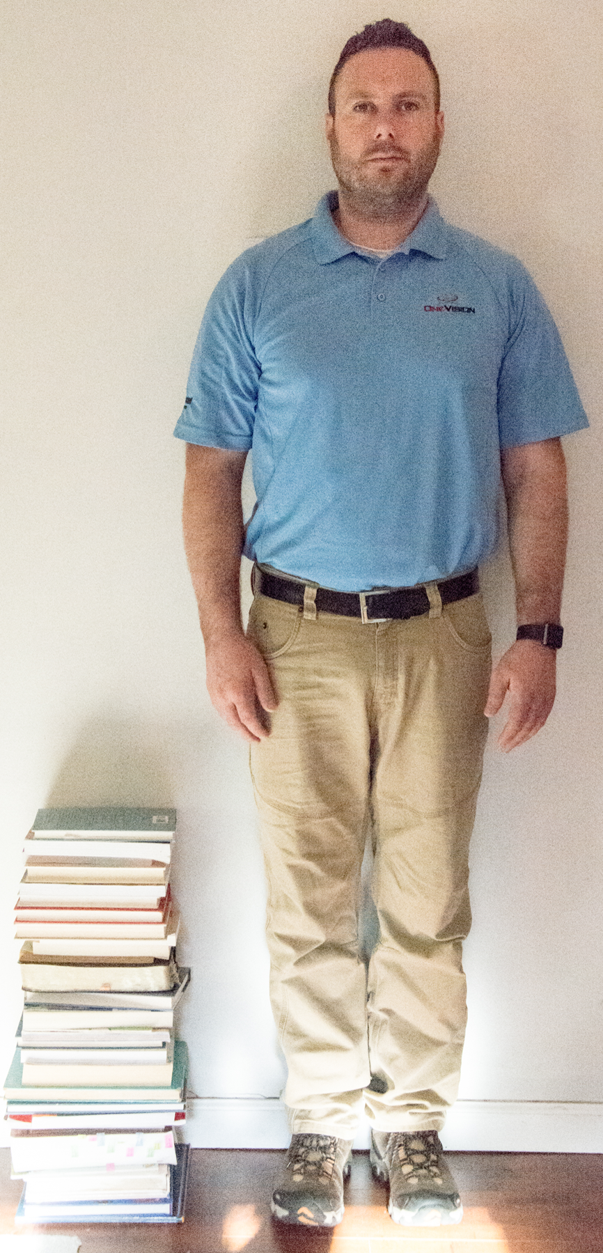 <p>Image of stack of books next to adult man. Stack reaches man's middle thigh.<br>
 </p>
