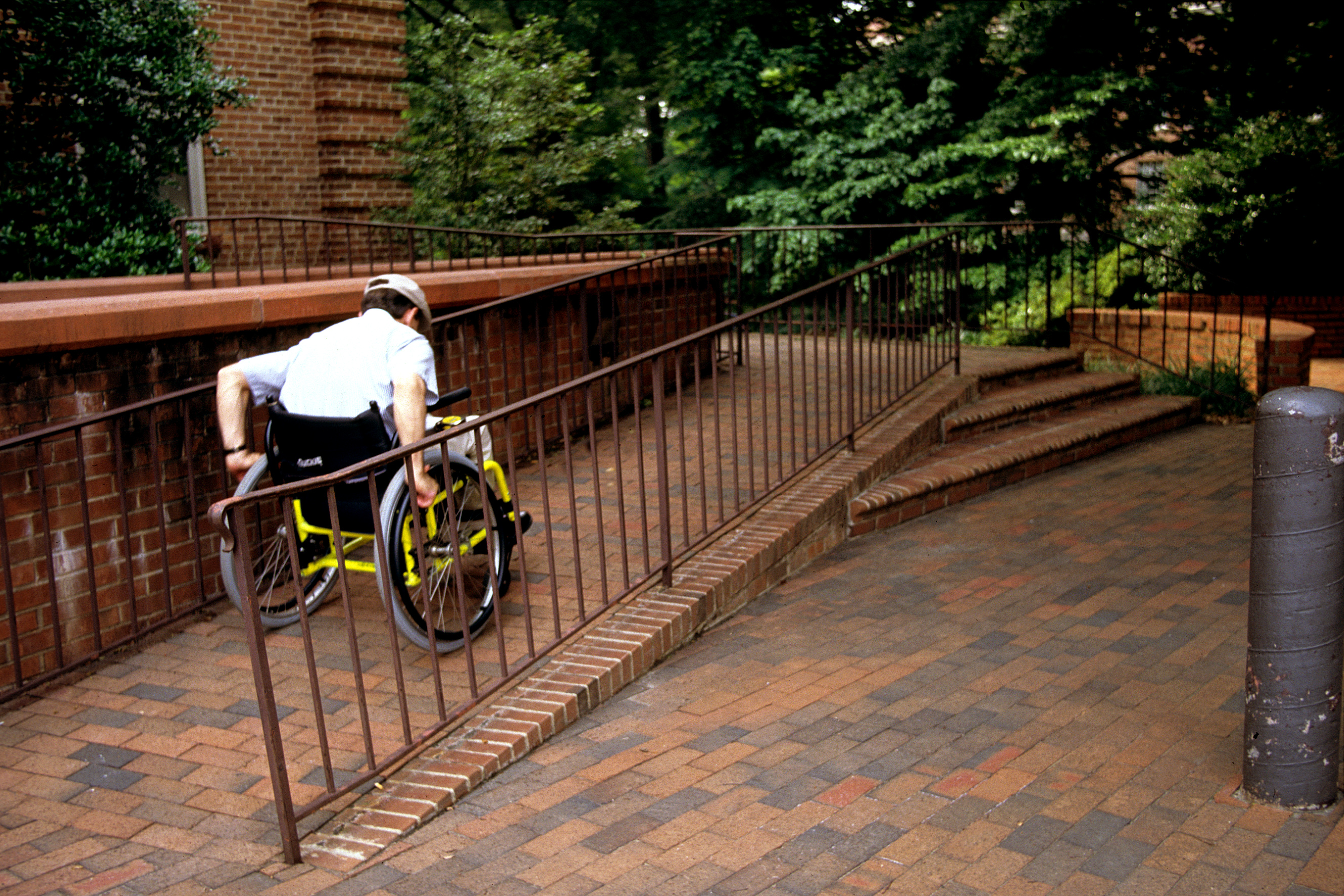 <p>Photo of a man in a wheelchair going up a ramp</p>
