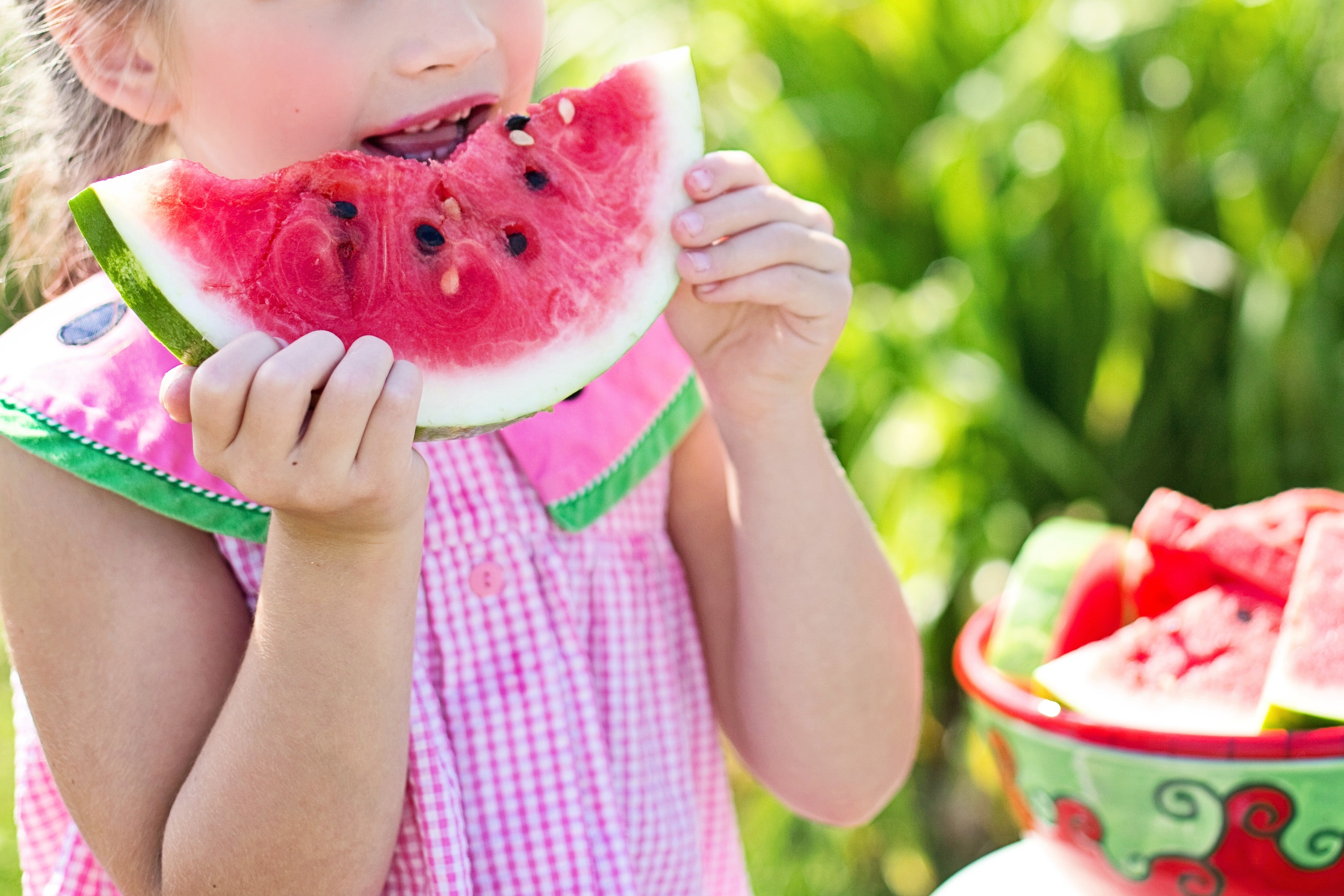 <p>little girl in watermelon sun dress eating a slice of watermelon </p>
