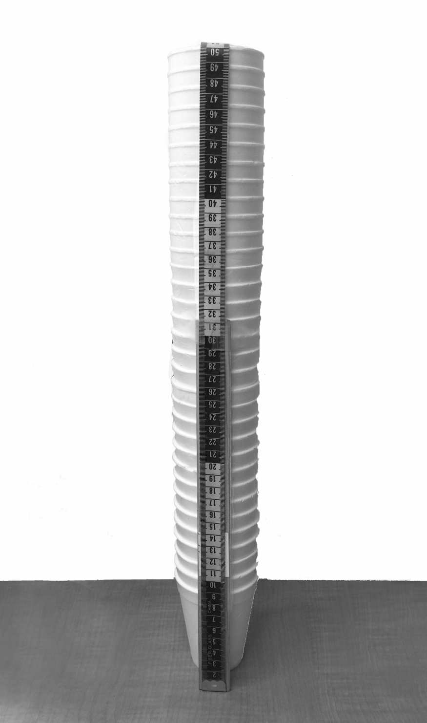 <p>Measuring tape used to measure stack of styrofoam cups </p>
