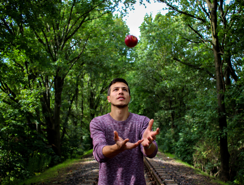 <p>A man tossing an apple up in the air</p>
