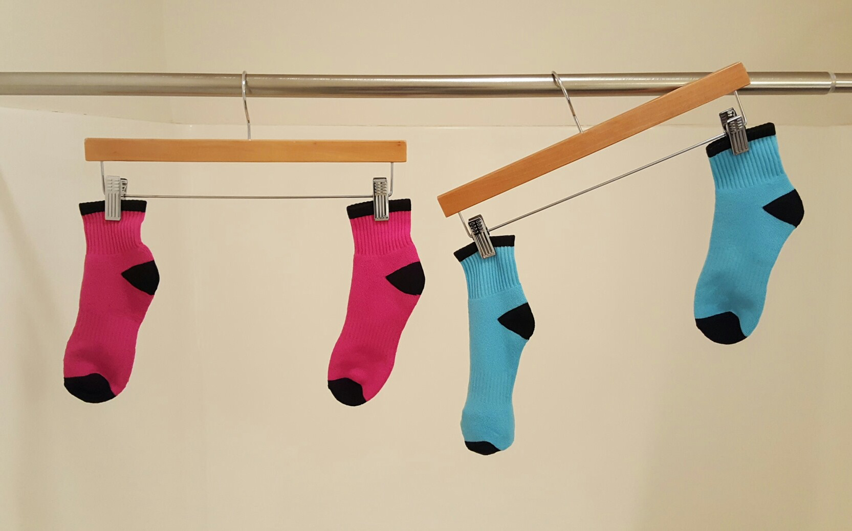 <p>Two clothes hangers hanging from a rod. Two pink socks, level. Two blue socks, not level.</p>

