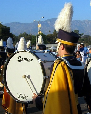 <p>Photograph of a man playing a drum in a marching band </p>

