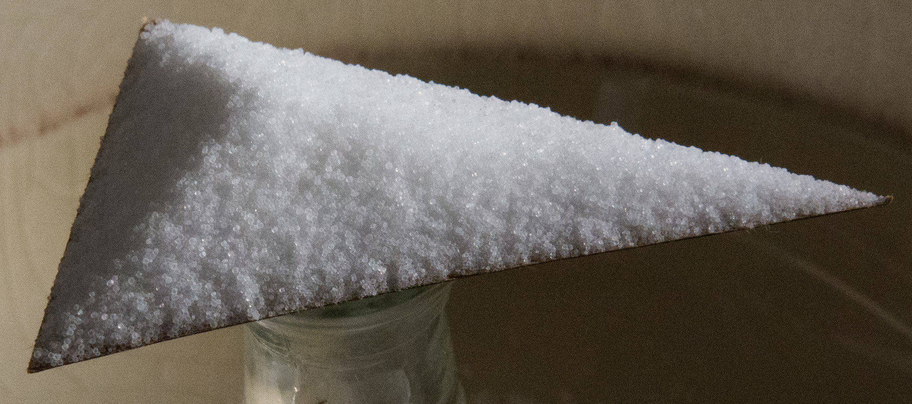 <p>Cardboard triangle on top of glass bottle, with salt on top of entire triangle.</p>
