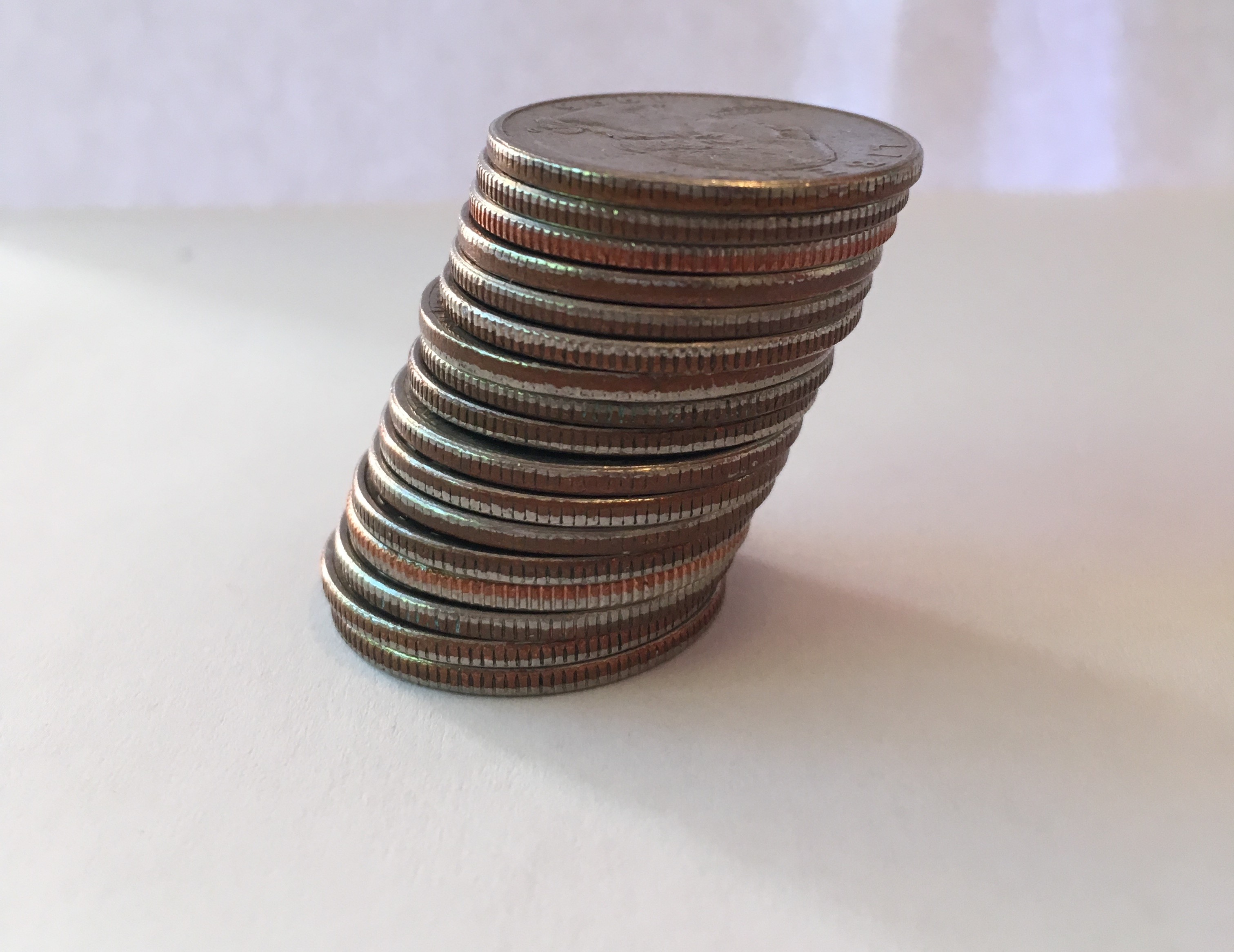 <p>A photo of a stack of coins, quarters, each one slightly off center from the one below it so that the stack appears to be leaning.</p>

