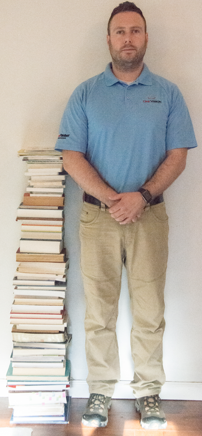 <p>Image of stack of books next to adult man. Stack reaches man's elbow.<br>
 </p>

