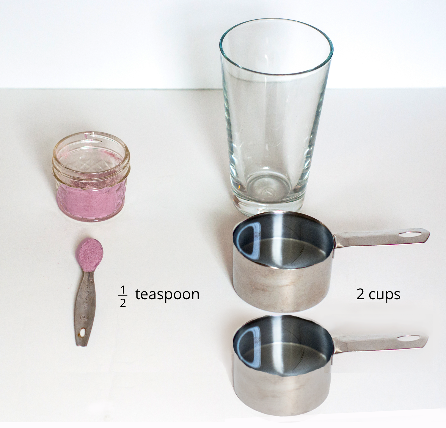 <p>A picture of a glass, drink mixture in a container, one half of a teaspoon of drink mix, and 2 measuring cups.</p>
