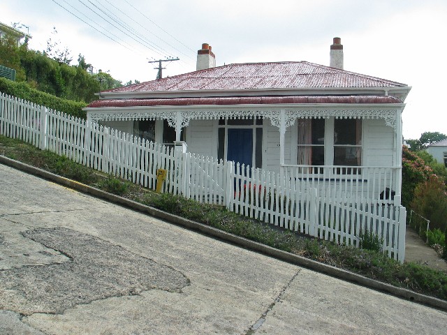 Photo of the house pictured in the warm-up from a different camera angle. The house is level The street has a steep angle.