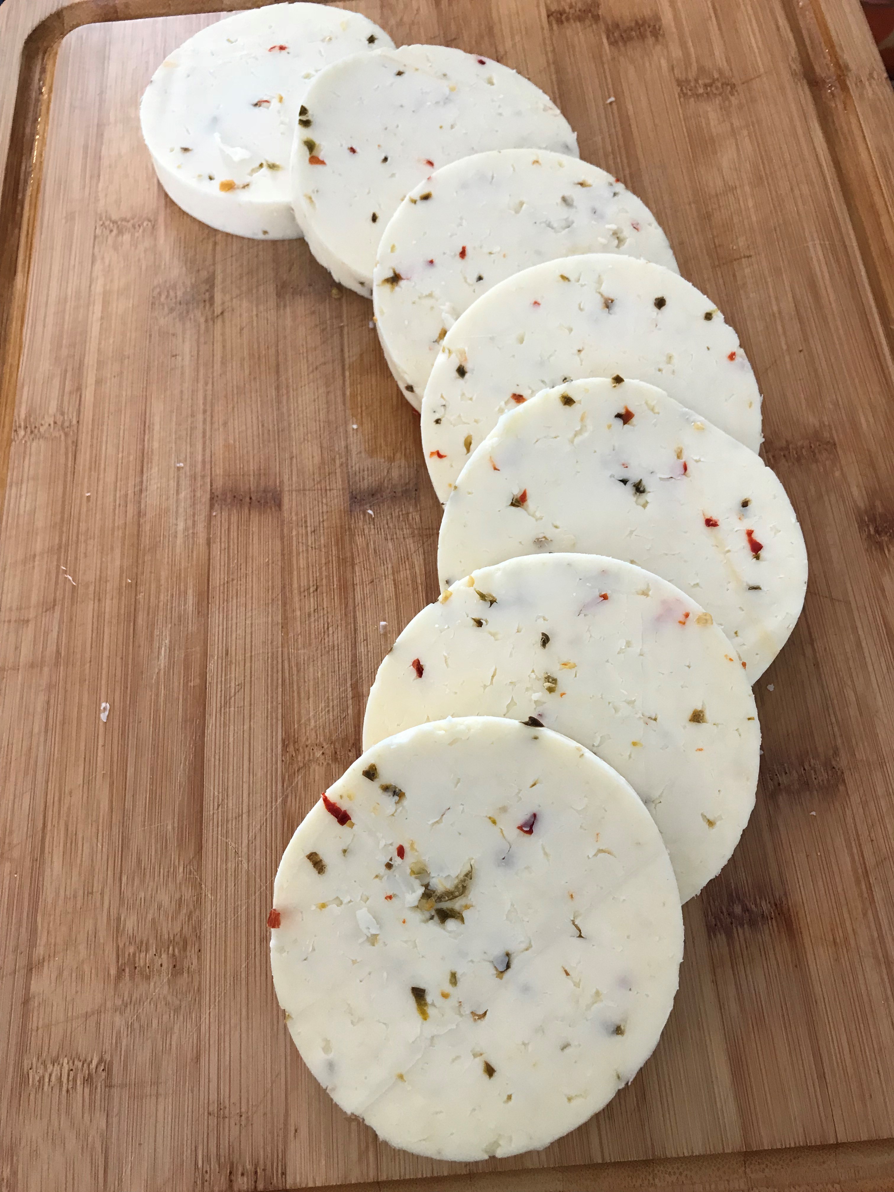 <p>Image of slices of cylindrical cheese spread out on a wooden cutting board.</p>
