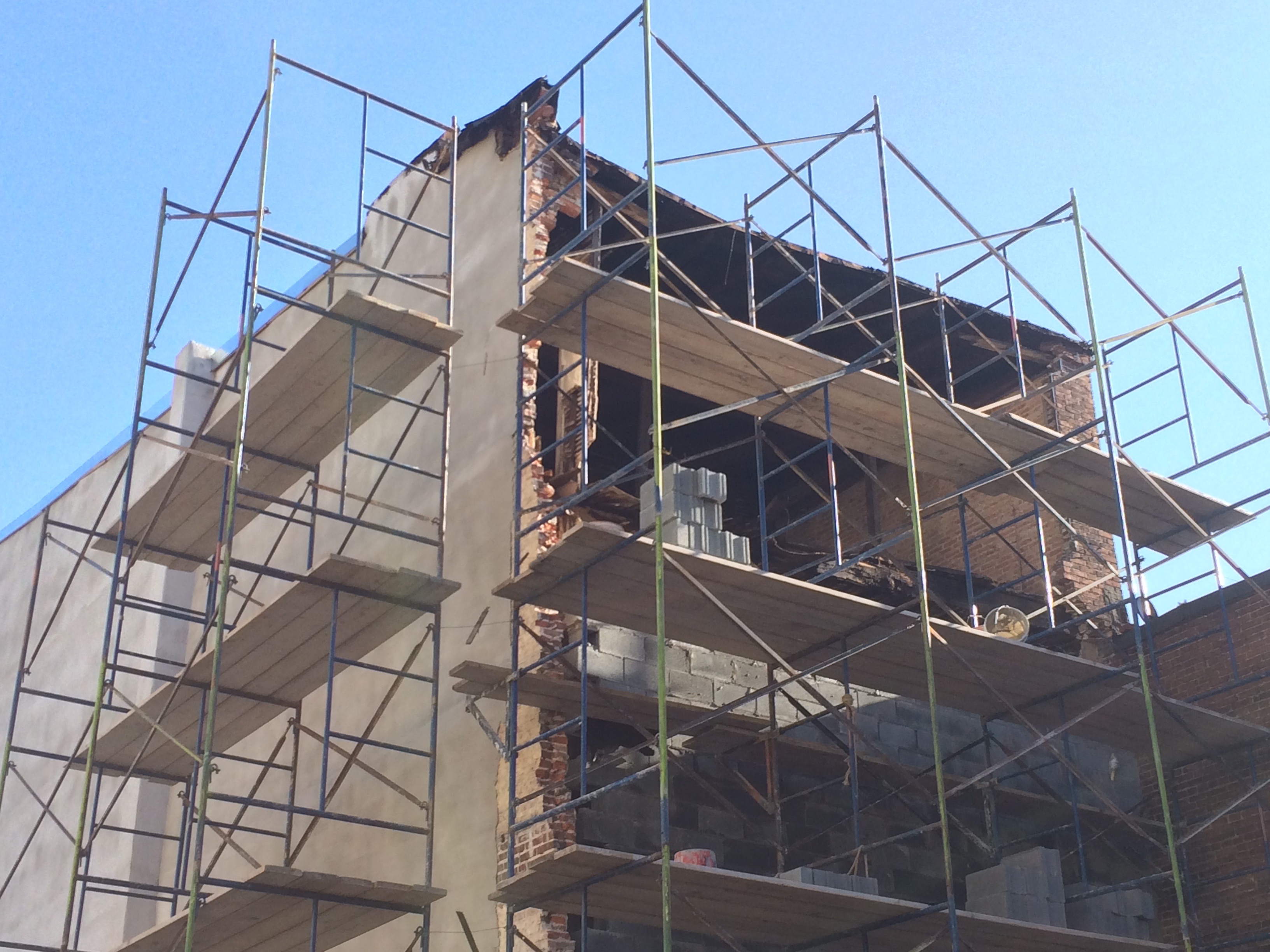 <p>A photo of scaffolding around a building. 3 stories of scaffolding are visible. One side of scaffolding has 4 vertical posts, with three sets of diagonal posts creating an X across each floor.</p>
